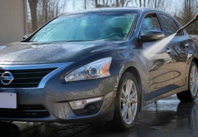 Ciemnoniebieski Nissan sedan spłukiwany wodą podczas mycia samochodu na zewnątrz