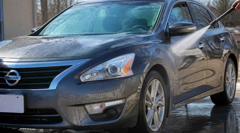 Ciemnoniebieski Nissan sedan spłukiwany wodą podczas mycia samochodu na zewnątrz